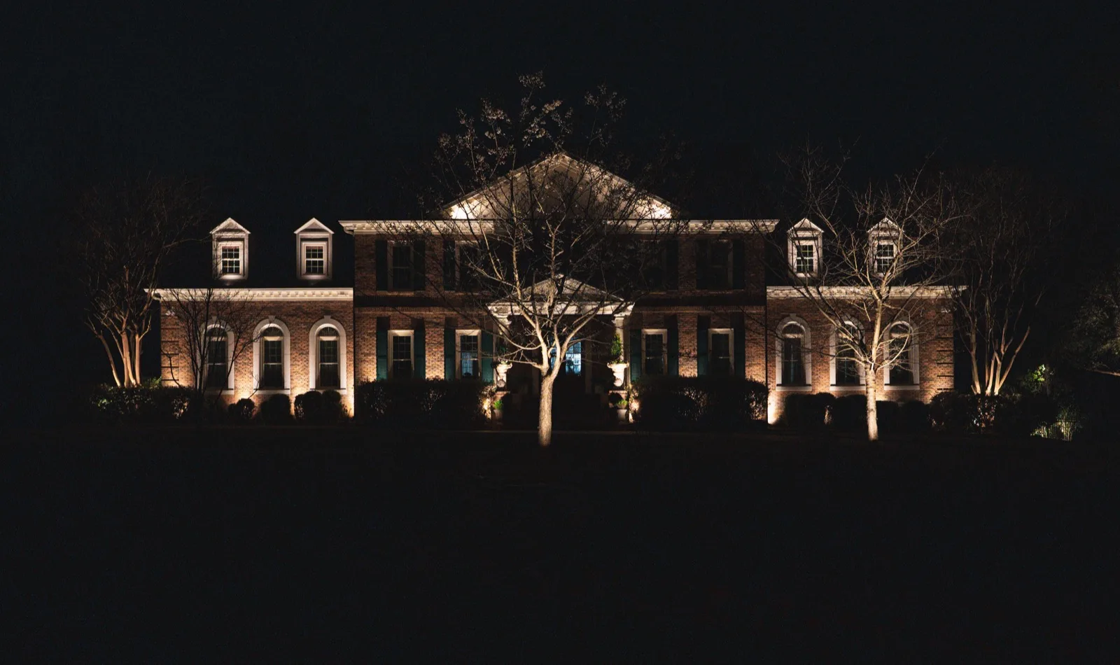 Federal-style brick home with up-lighting at night