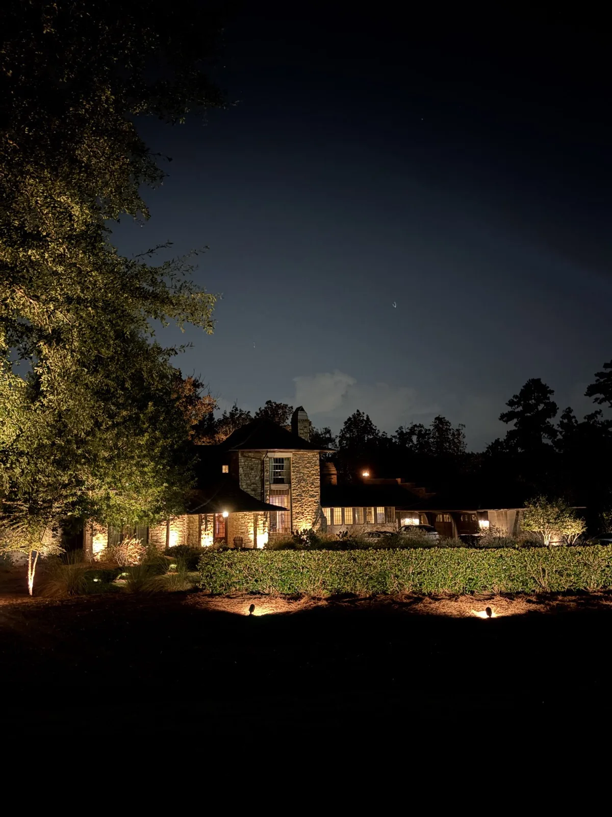 Stone home with garden landscape lighting at night